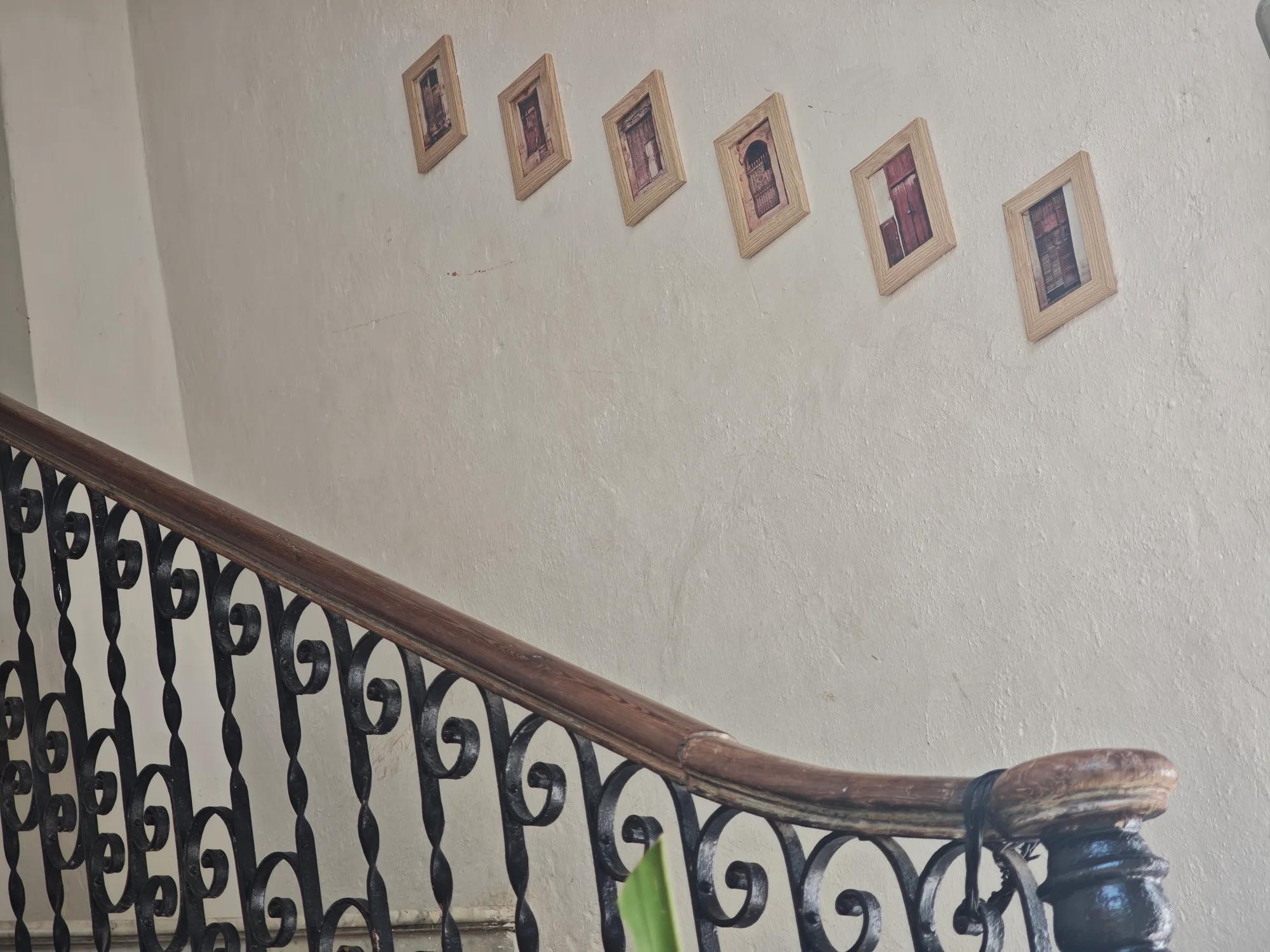 Seis fotos enmarcadas de puertas colgadas en diagonal sobre la barandilla de hierro forjado de la escalera
