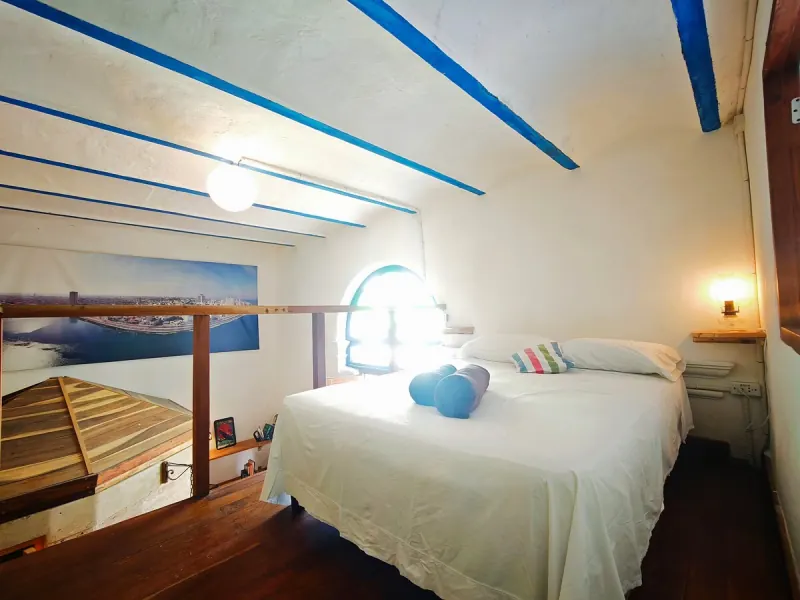 Chambre en mezzanine avec un lit double et une poutre bleue