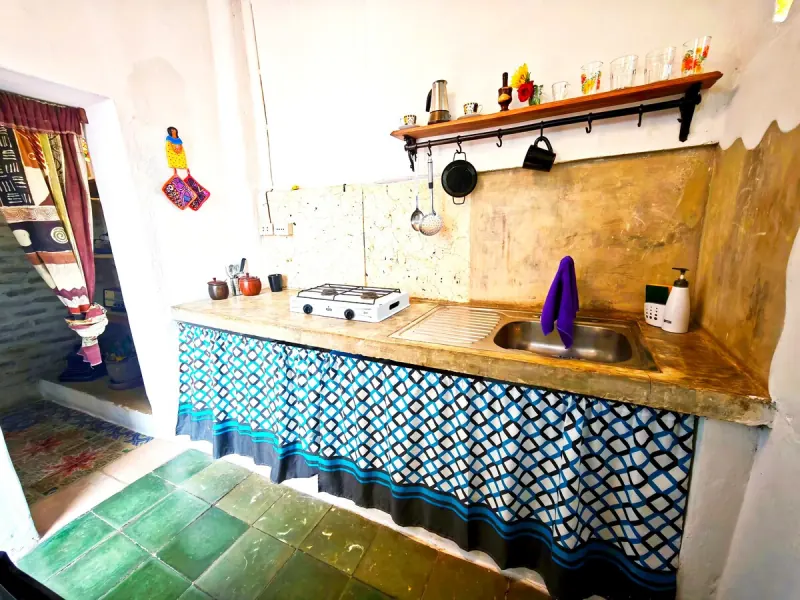 Cuisine avec un plan de travail, un évier et un rideau à carreaux