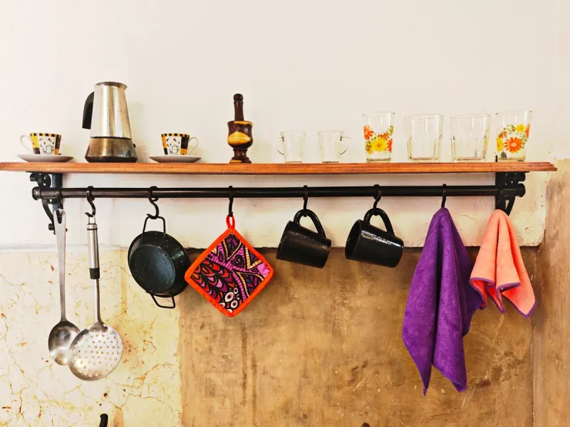 Étagère avec des tasses, une cafetière et des verres colorés