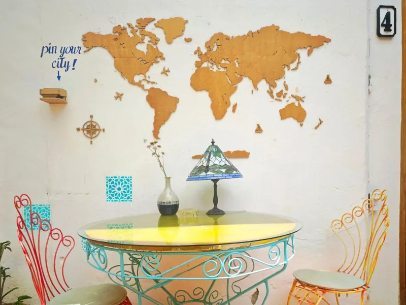 Table en fer dans le patio avec un planisphère en bois sur le mur