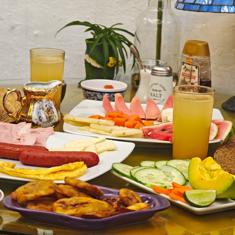 Petit-déjeuner servi avec des fruits, des œufs, de la charcuterie, des jus et du café