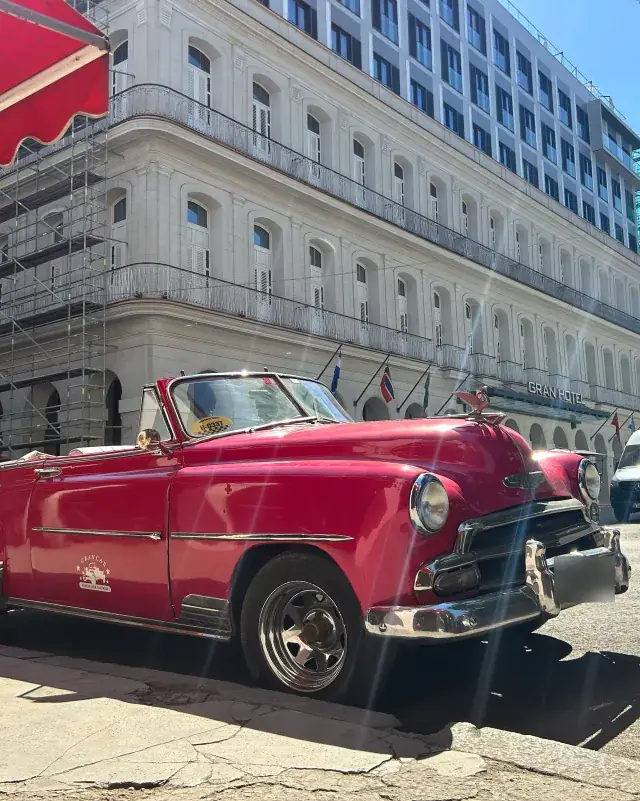 Voiture ancienne décapotable rouge pour le tour en décapotable, devant un grand hôtel de La Havane
